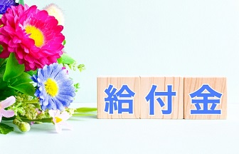 花束の右横に給付金と書かれた積み木が置かれている画像