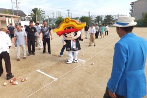 ゲートボールの試合が行われているコート外で、忠岡町マスコットキャラクター「ただお課長」が歩き、それを参加者が楽しそうに眺めている様子を撮影した写真
