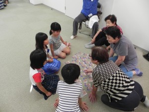 福祉センターで子どもたちとご年配の方たちがカードを使った遊びを一緒に楽しんでいる写真