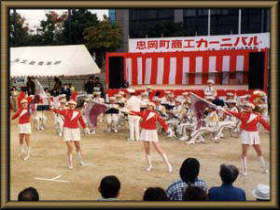 グラウンドで赤白の服を着た人たちが踊っている写真