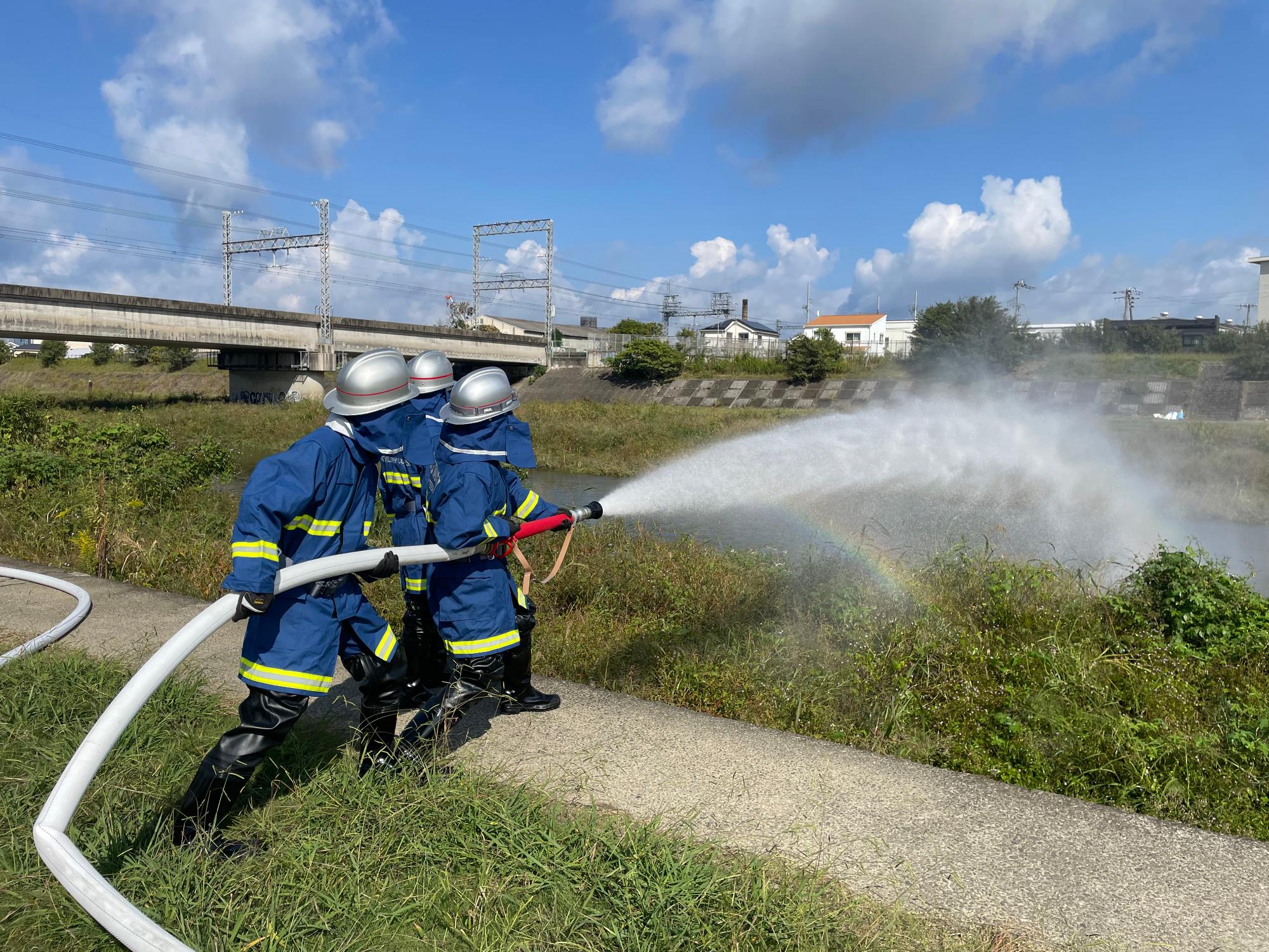 大津川にて消防団員により放水が行われている。