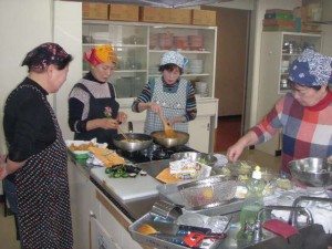 講座における調理作業の実施風景の写真。写真中央に、受講者がコンロを用いて加熱調理を行う様子が確認できる